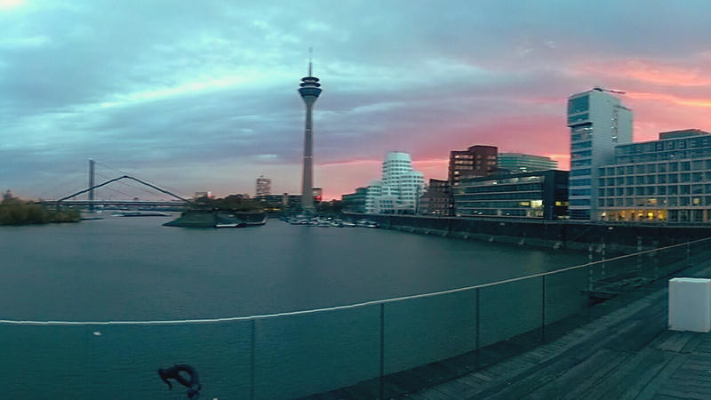 Example image show a cityscape at dusk with modern buildings, a river, and a prominent tower. The sky is painted with hues of pink and blue, reflecting on the water. The scene is calm and picturesque, capturing the essence of a serene urban evening. Example image show a cityscape at dusk with modern buildings, a river, and a prominent tower. The sky is painted with hues of pink and blue, reflecting on the water. The scene is calm and picturesque, capturing the essence of a serene urban evening.